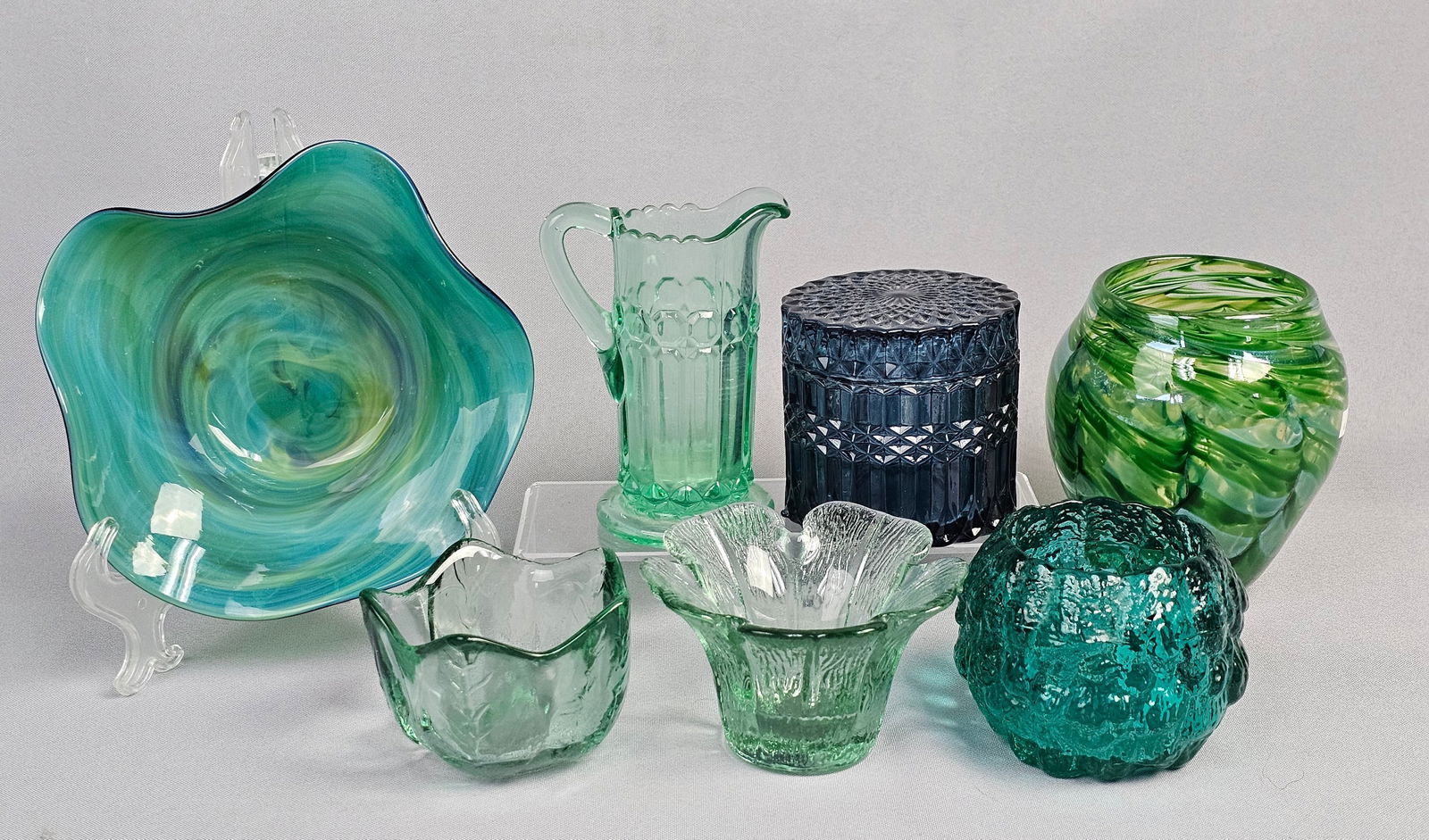 A Collection of Seven Glass Artware and Decorative Objects: Ruffled Round Bowl, exhibiting swirling patterns of blue and teal, with a signature etched into its base, "Grant?". Accompanying this are six additional pieces of glass artware and decorativ