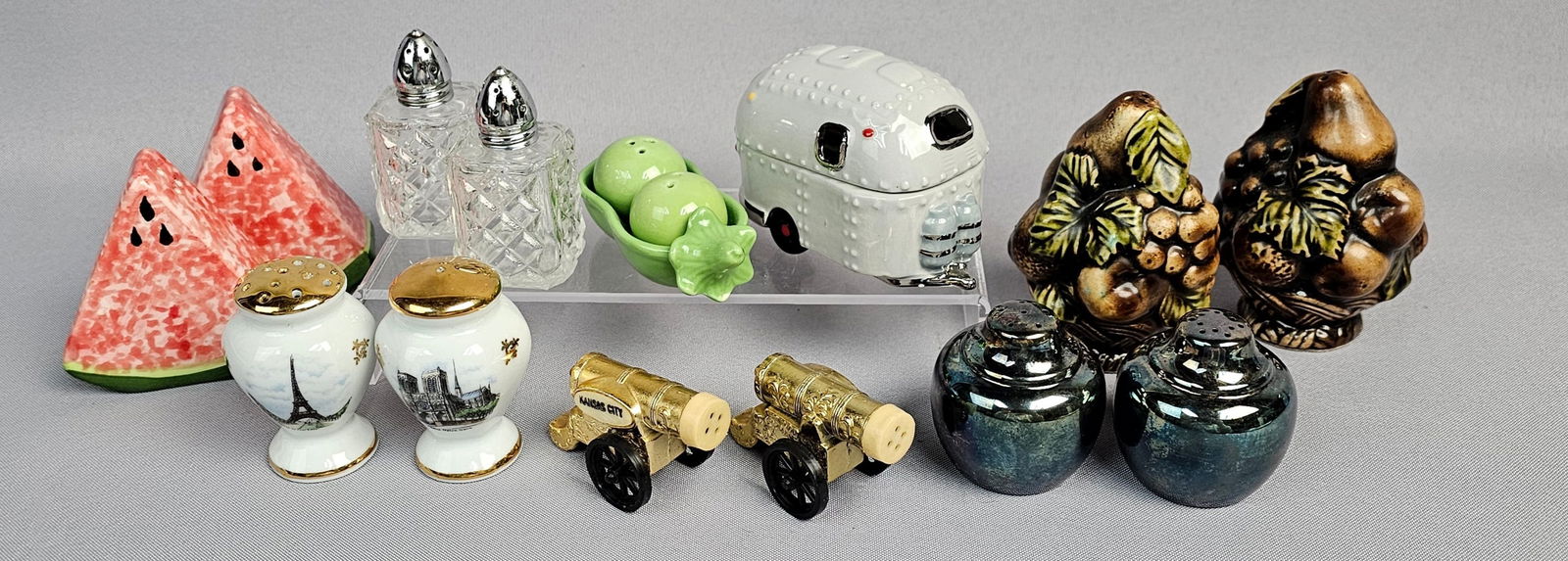 A Collection of Novelty Salt and Pepper Shakers including Airstream Camper, Limoges and NARCO: A collection of novelty salt and pepper shaker components, executed primarily in glazed ceramic and porcelain, supplemented by glass, plastic, and metal models. Notable sets include a two-piece glazed