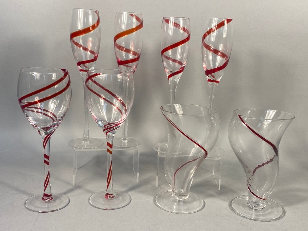 Eight Pier 1 Double Swirl Red Glasses: A collection of eight Pier 1 'Double Swirl Red' glassware, comprising four champagne flutes with slender stems, two traditional wine glasses, and two uniquely shaped, organically curved stemmed vessel