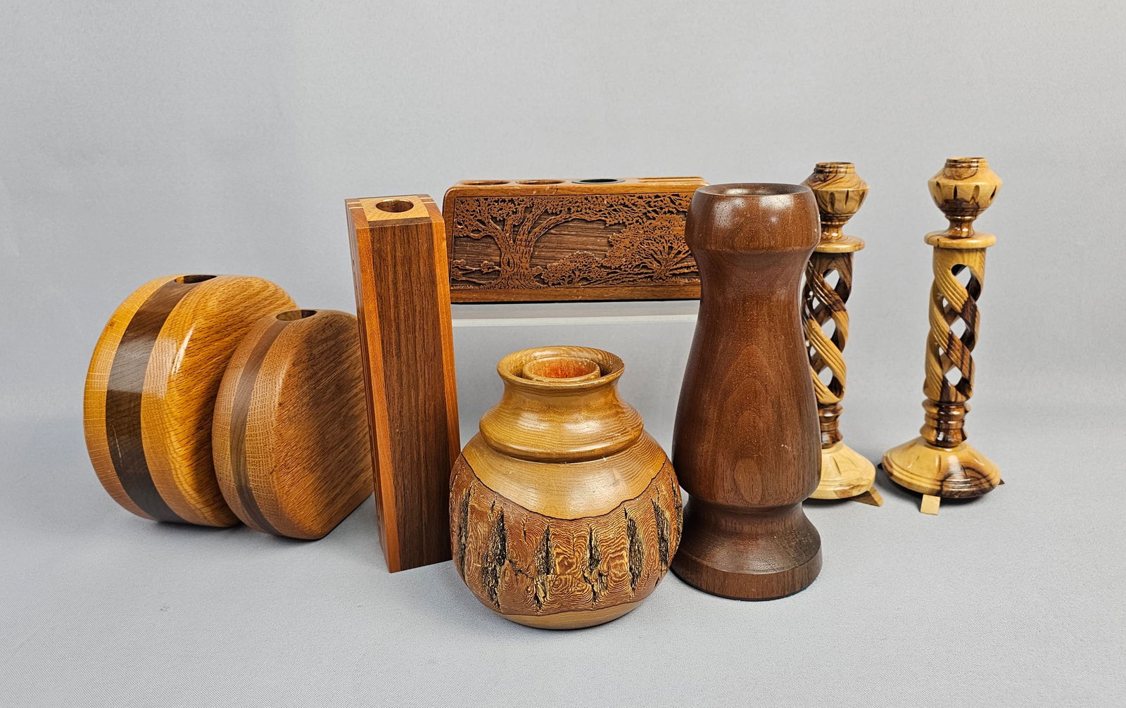 A Collection of Eight Wooden Vessels and Desk Accessories: A collection of eight pieces of contemporary studio craft woodwork, utilizing turning, carving, and segmented construction techniques, primarily featuring mixed hardwoods such as oak, walnut, and burl