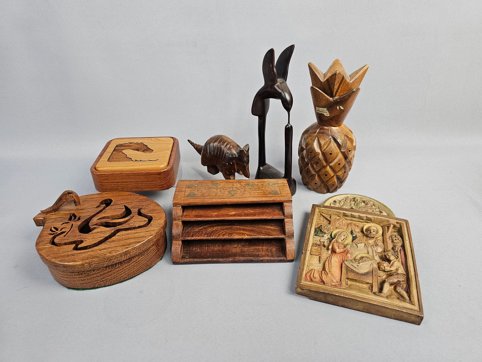 A Collection of 7 Decorative Wooden Objects Inc a Carved Nativity Scean: A collection of decorative objects primarily composed of carved and inlaid wood folk art and souvenir items. The collection includes two figural wood carvings: a dark wood hummingbird or bird on a sta