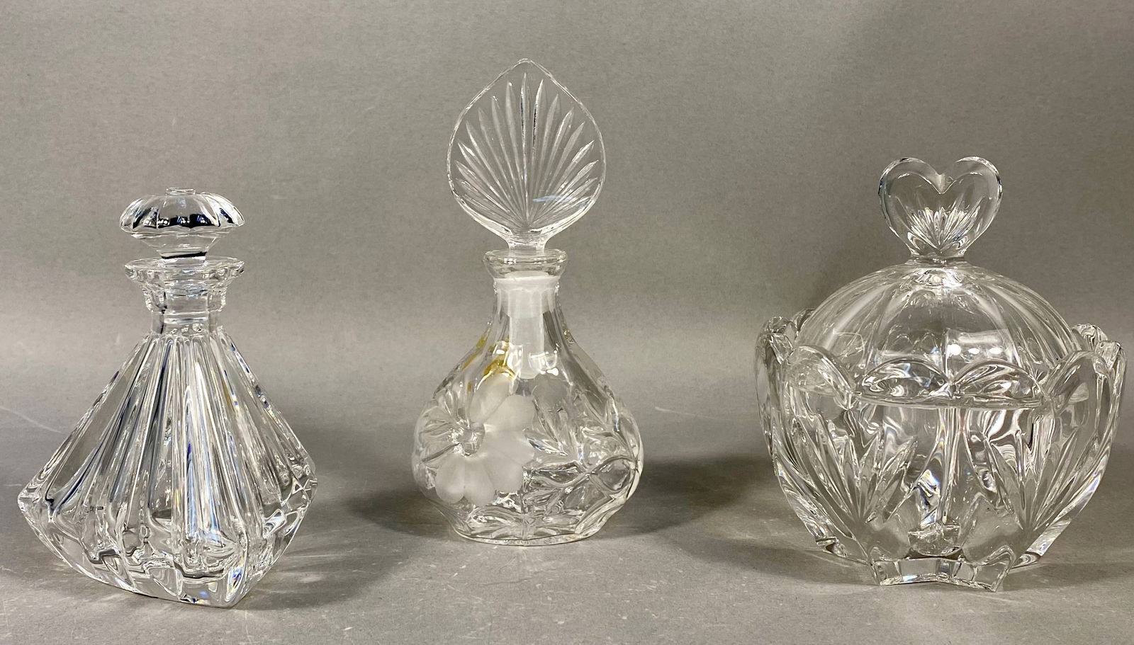 A Trio of Cut Lead Crystal Perfume Bottles and Covered Jar by Marquis by Waterford and Princess: A collection of three pieces of clear, heavy cut lead crystalware, including two perfume bottles and one covered jar. The first item is a geometric, highly faceted perfume bottle identified by etchin