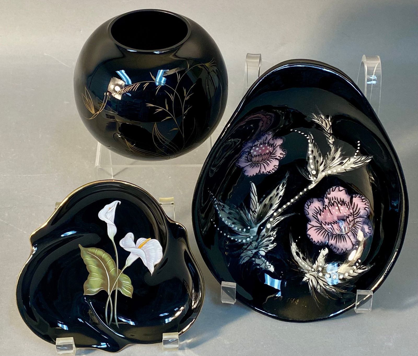 A Trio of Mid-Century Modern Black Glazed Ceramic and Glass Decorative Wares, including Sascha: A collection of three decorative items crafted from high-gloss black glazed ceramic, porcelain, or glass exhibiting a Mid-Century Modern aesthetic. The lot includes one large asymmetrical freeform bow