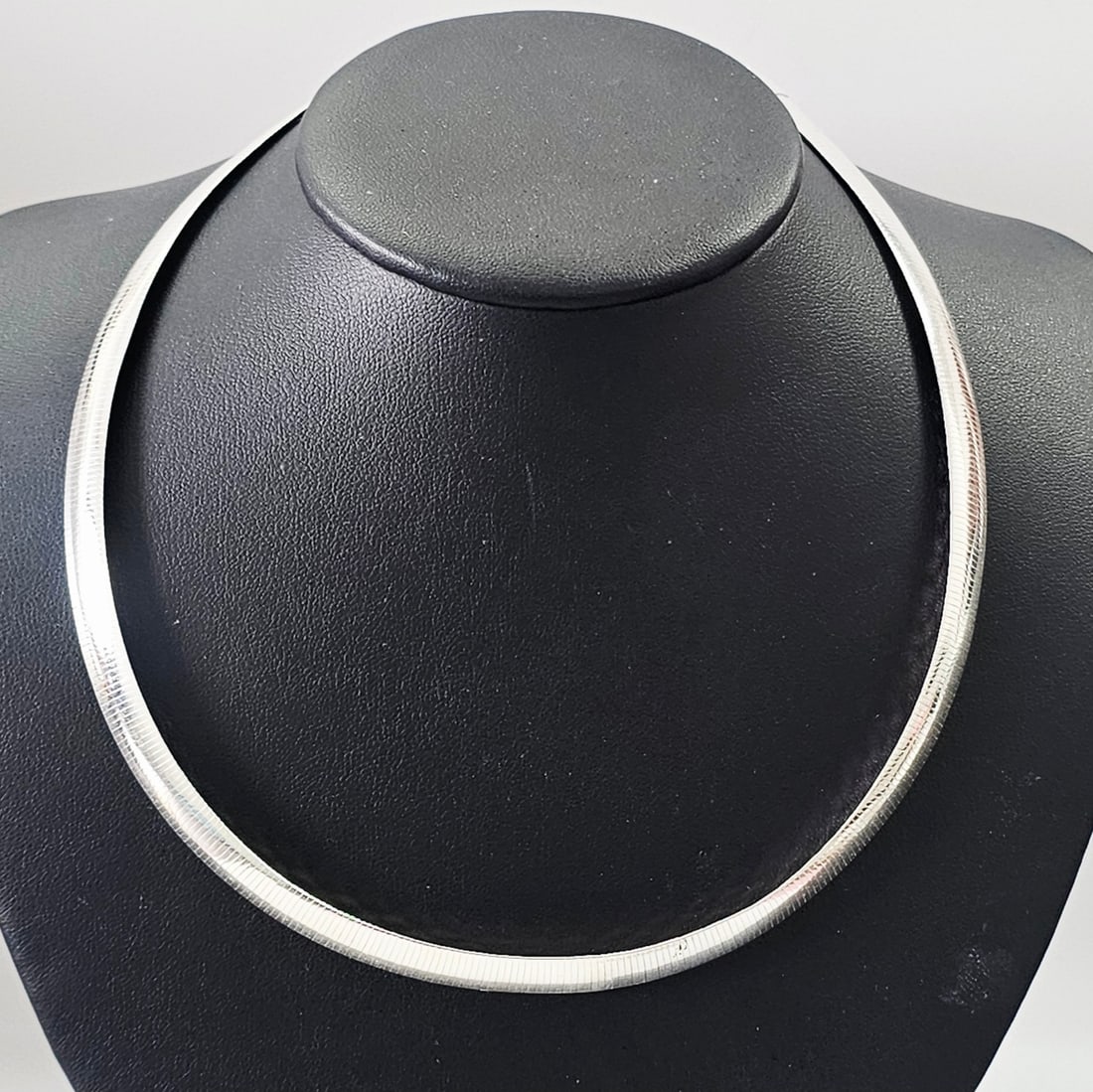 Milor Italian 950 Silver Omega Chain Necklace: An Italian 950 silver omega chain necklace by Milor. The piece features a flat, flexible, segmented design with a textured finish on one side and a polished surface on the reverse. It is secured with