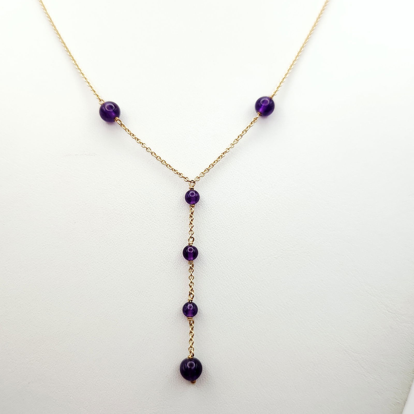 14K Gold Lariat Necklace 3.6 Grams: A contemporary lariat or Y-chain necklace constructed of 14 karat yellow gold fine link chain. The design incorporates a total of six polished, spherical deep purple gemstone beads, likely amethyst, i