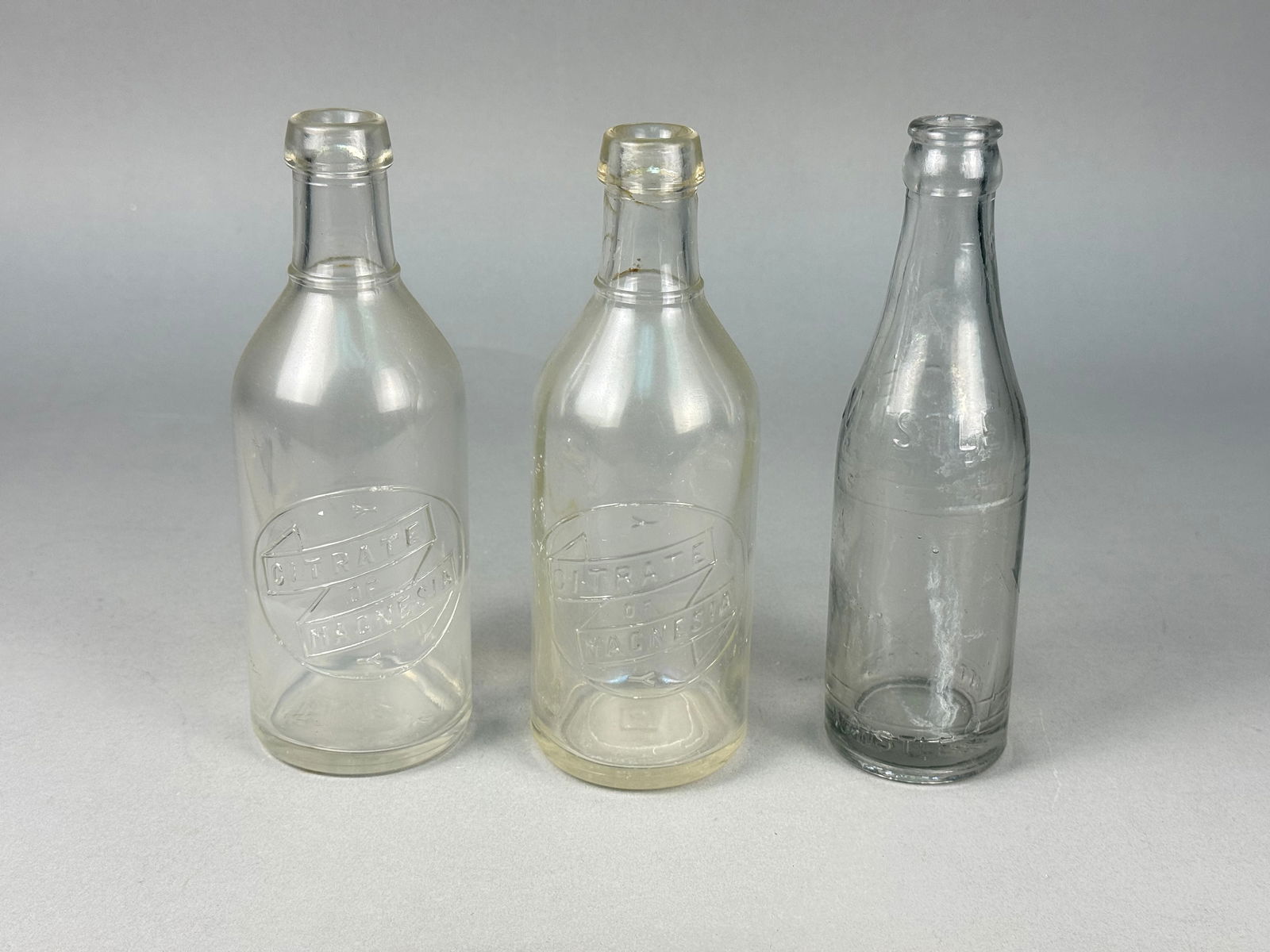 A Trio of Vintage Clear Glass Bottles including Citrate of Magnesia and Fisher Bottling Co. (1 of 9)