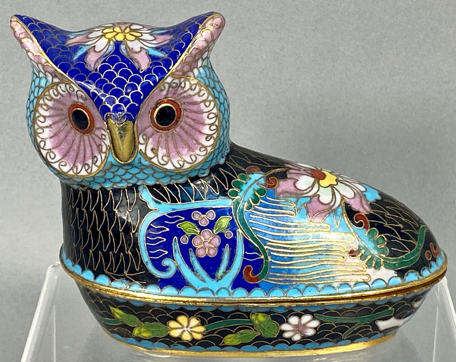 A Chinese Cloisonne Enamel Owl Covered Box 20th Century: A Chinese cloisonne enamel covered box in the form of a seated owl. This two-piece decorative object is constructed with gold-toned metal cloisons filled with turquoise, lapis blue, pink, green, and w