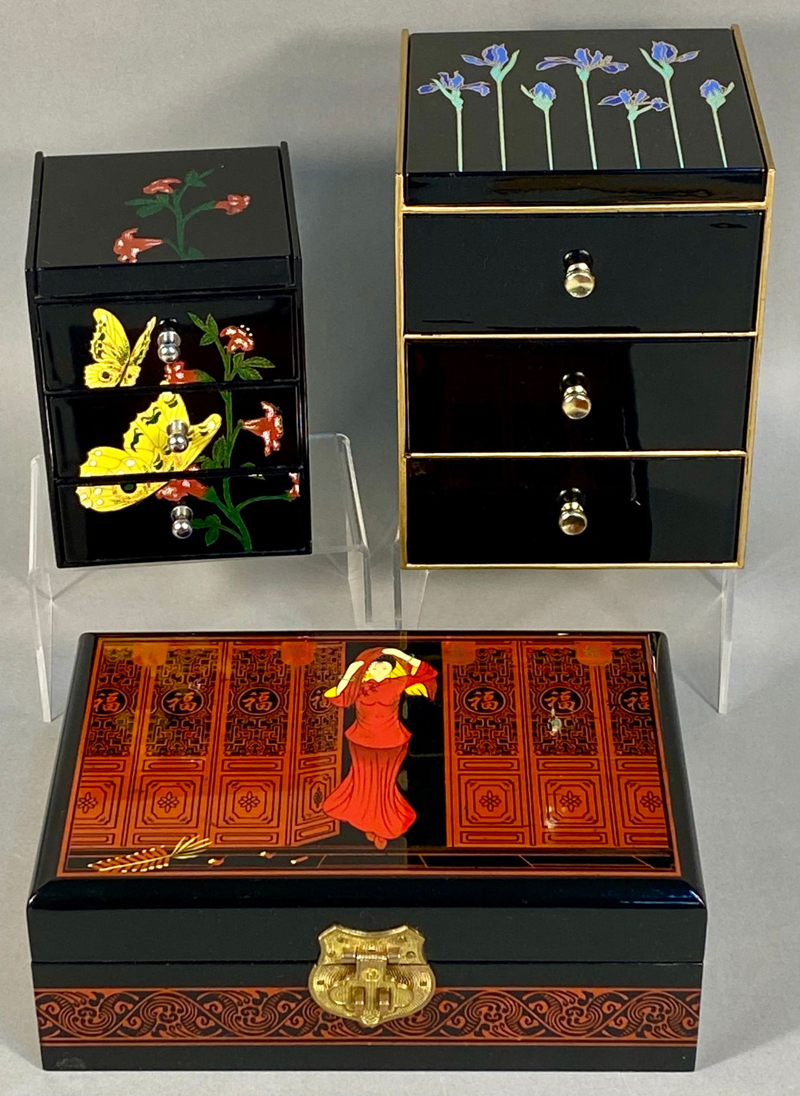 Three Asian-Style Lacquered Jewelry Chests and Storage Boxes including Otagiri: A group of three Asian-inspired jewelry storage items consisting of two upright chests and one rectangular lidded box. The first upright chest is constructed of black lacquered material decorated with
