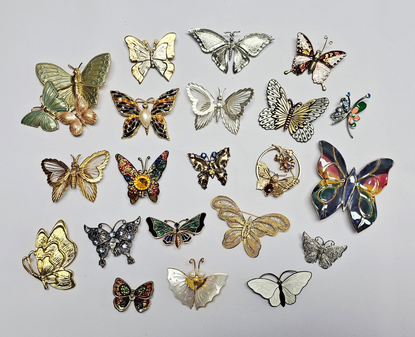 Vintage and Contemporary Butterfly Brooches Inc Monet: A collection of butterfly-themed brooches and pins featuring various styles and materials. The group includes designs in gold-tone and silver-tone metals, with several pieces accented by enamel, wire