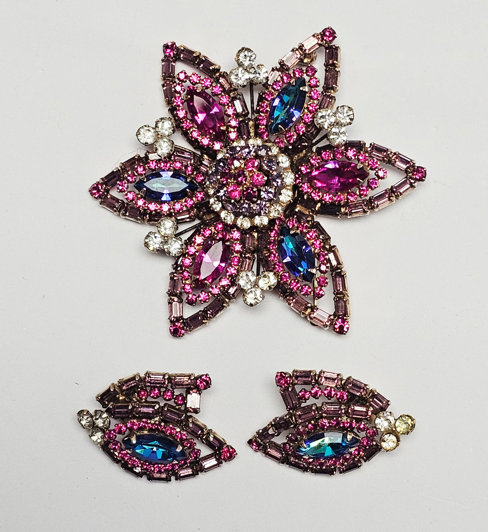 Vintage Weiss Rhinestone Flower Brooch & Earrings: A Weiss costume jewelry demi-parure consisting of a starburst-form flower brooch and a pair of matching clip-on earrings. The set is crafted in gold-tone metal and embellished with multi-colored