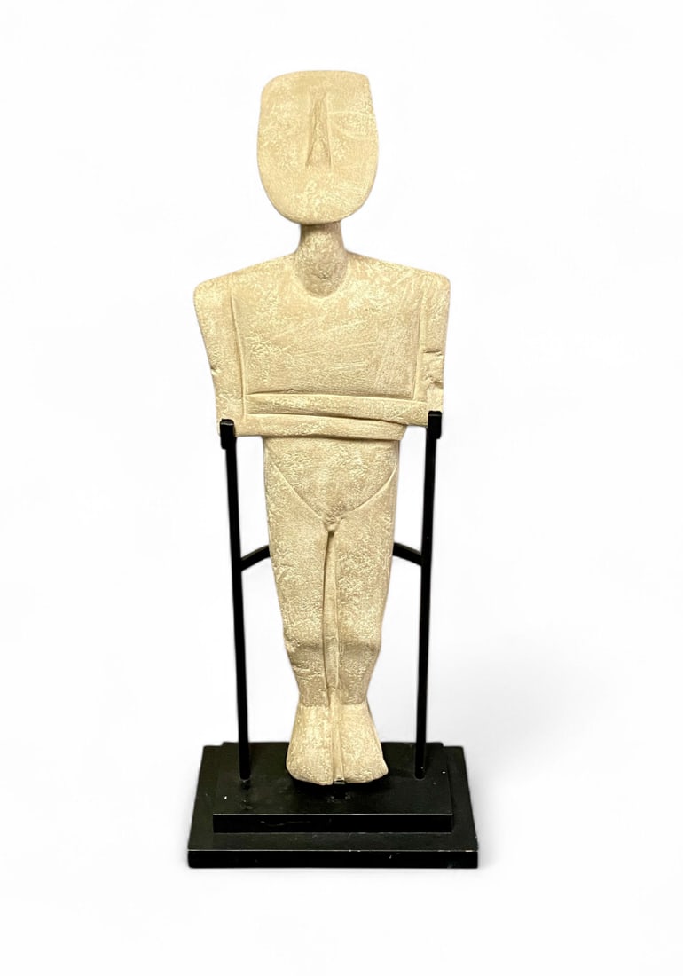 Mid 20th Century Greek Cycladic Style Idol Sculpture on Stand: A mid 20th-century Greek Cycladic style idol sculpture. The figure is crafted from a stone-like composite material with a textured, off-white finish that is intentionally weathered to simulate antiqui