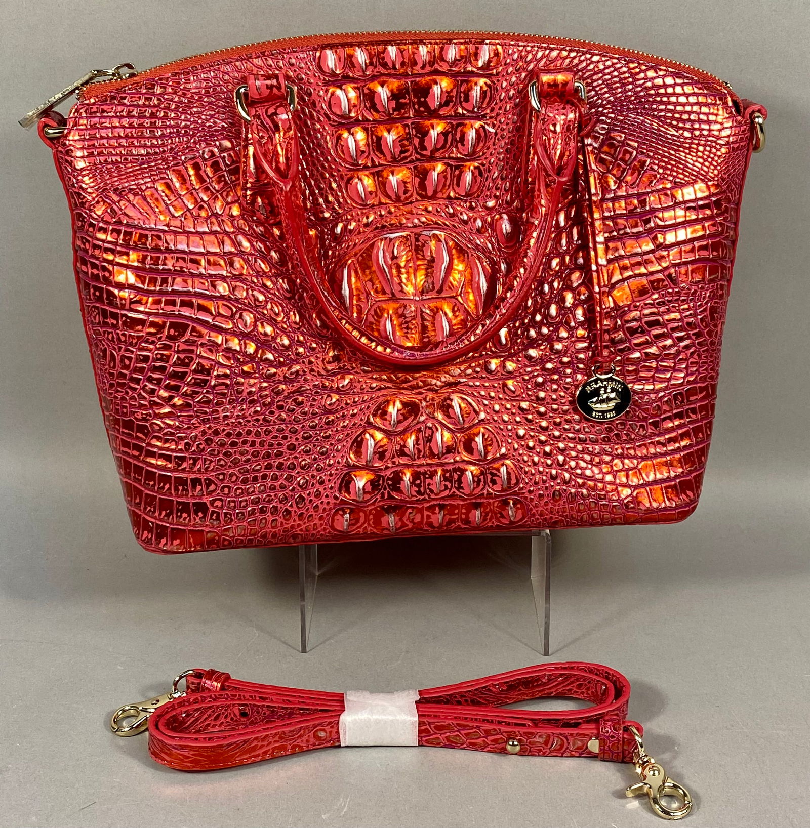 Brahmin Melbourne Large Duxbury Satchel: A Brahmin Large Duxbury Satchel featuring an iridescent reddish-pink Melbourne crocodile-embossed leather exterior. The bag is constructed with dual rolled top handles, a zip-top closure, and includes