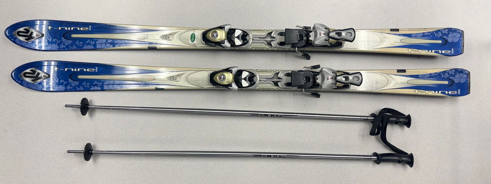 A Pair of K2 T-Nine Echo Alpine Skis with Atomic Poles and High Sierra Bag: A pair of K2 T-Nine Echo alpine skis. The black bases are marked with a pink ribbon motif. The skis are fitted with Salomon S710 adjustable bindings. Included is a pair of Atomic Beta Pulse ski poles,