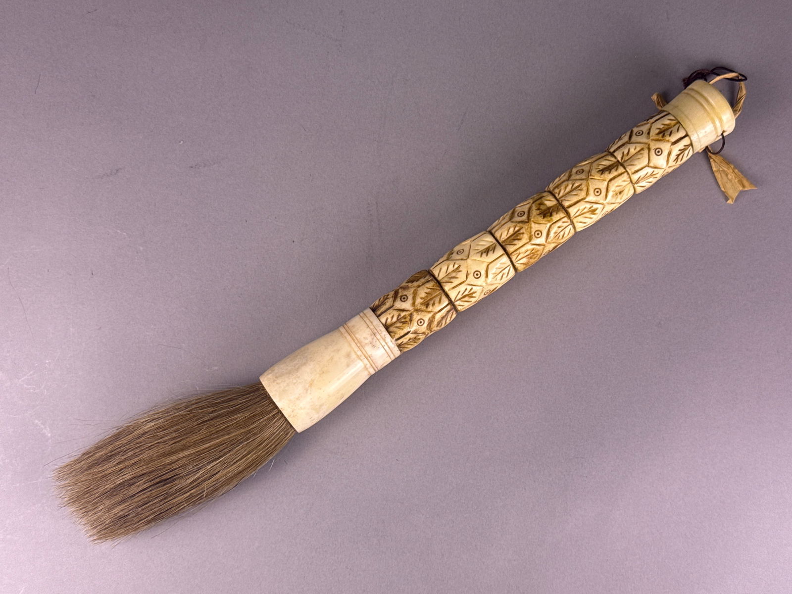 Carved Bone Calligraphy Brush with Lucky Pattern: Carved bone calligraphy brush featuring a lucky pattern. The handle is constructed from multiple carved bone segments, each decorated with repeating geometric and foliate patterns punctuated by small