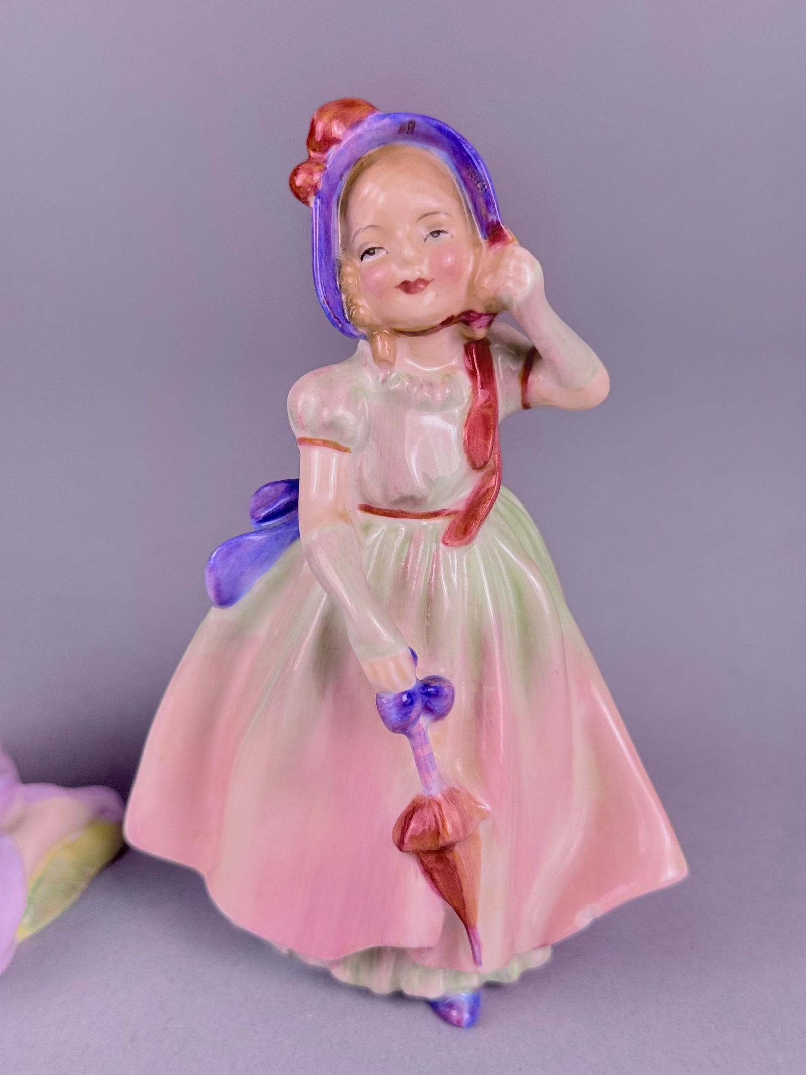 Two Royal Doulton Porcelain Figurines Mary Had a Little Lamb HN 2048 and Babie HN 1679: Two hand-painted bone china figurines produced by Royal Doulton. The first figurine, titled Mary Had a Little Lamb (model HN 2048), depicts a seated girl in a lavender dress with a blue sash and headb