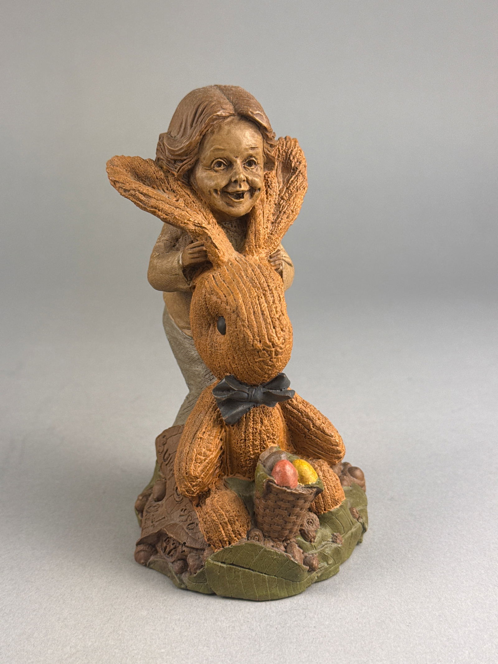 Tom Clark for Cairn Studio Bunny Gnome Figurine, 1990: A Tom Clark for Cairn Studio molded resin figurine titled Bunny, dated 1990. The polychrome piece depicts a smiling figure holding a large, textured rabbit, positioned beside a small basket
