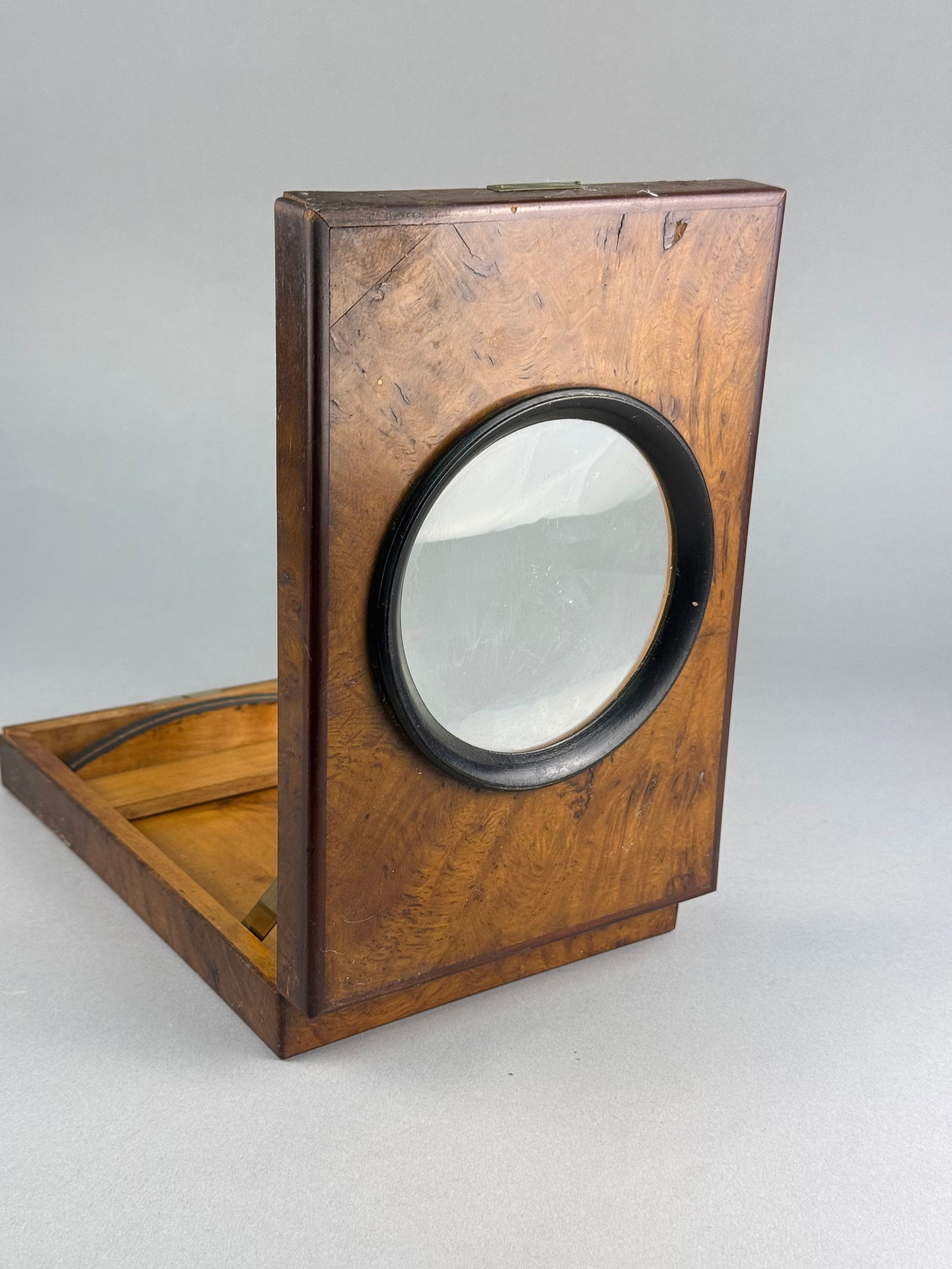 Antique French Burled Wood Graphoscope: This antique French graphoscope is constructed from a rectangular wooden box featuring a burled wood veneer. The hinged lid contains a large central circular magnifying lens set within a black-painted