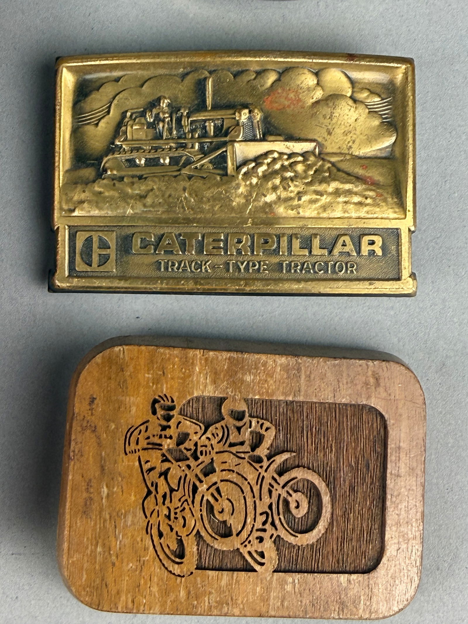 A Collection of Vintage Belt Buckles including Mark Martin #6 Valvoline Racing and Caterpillar: A collection of vintage belt buckles featuring a Mark Martin #6 Valvoline Racing limited edition buckle. The Mark Martin buckle is constructed of metal with blue, white, and red enamel accents,