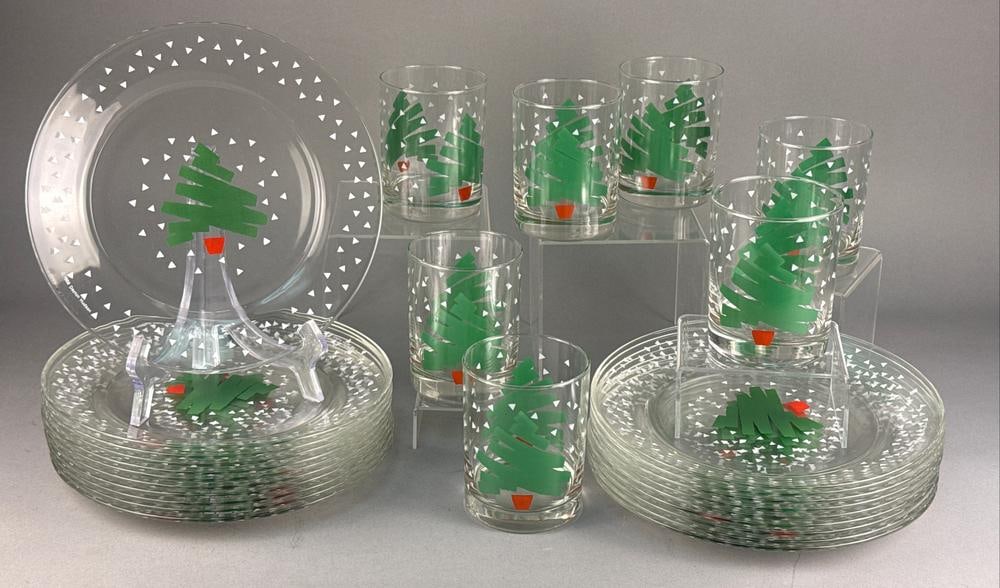 A Collection of Dayton Hudson Arcoroc Tree & Confetti Pattern Glassware: A collection of clear glass holiday-themed tableware in the Tree & Confetti pattern, manufactured by Arcoroc for Dayton Hudson. The set consists of circular plates and cylindrical tumblers. Each piece
