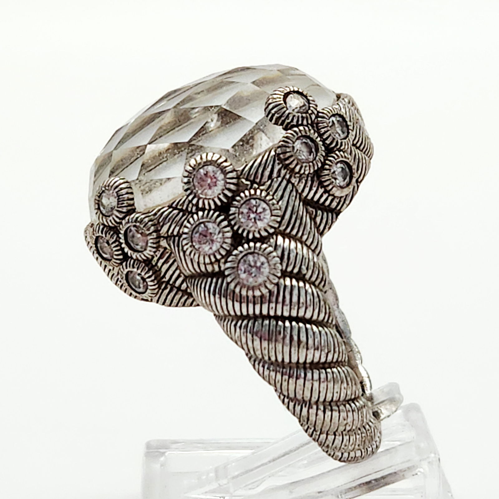 Judith Ripka Sterling White Stone Ring 12.7 Grams: A sterling silver ring by designer Judith Ripka featuring a large, oval, faceted white central stone. The mounting displays a heavily textured design with signature twisted cable and rope patterns on