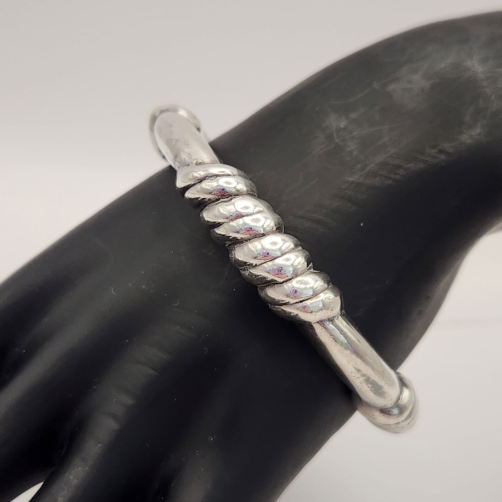 Carolyn Pollack Sterling Bangle Bracelet 23.7 Grams: This sterling silver bangle bracelet is attributed to Carolyn Pollack and features a Southwestern style design. The piece is constructed with a textured pattern consisting of alternating smooth and ri
