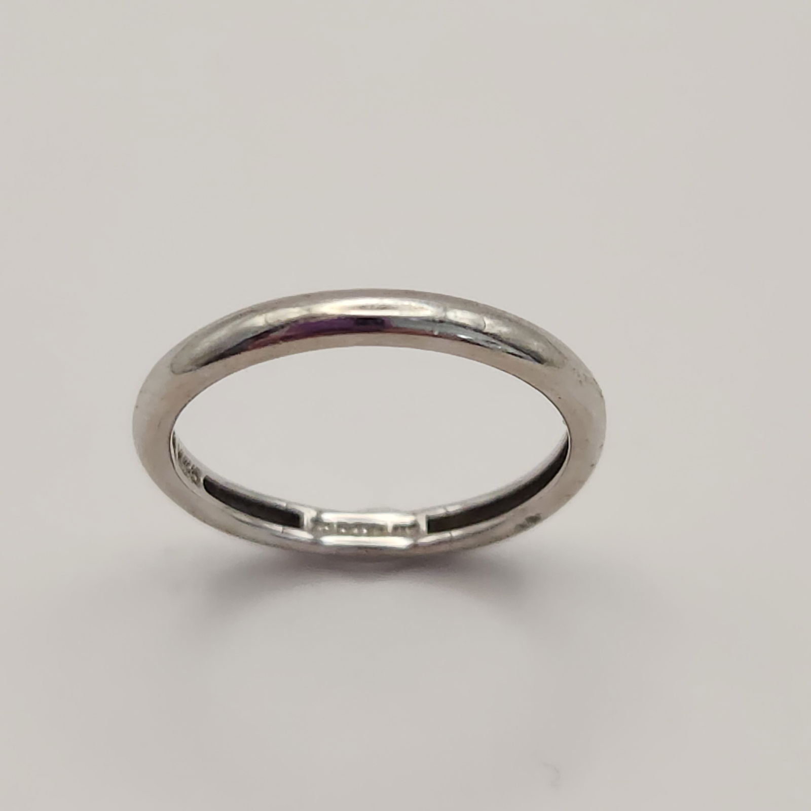 14k White Gold Band Ring 1.2 Grams: This 14k white gold ring is designed as a simple, thin, high-polish rounded band. The interior of the band contains an illegible maker's mark followed by a purity stamp. Size: 5 Weight: 1.2 grams