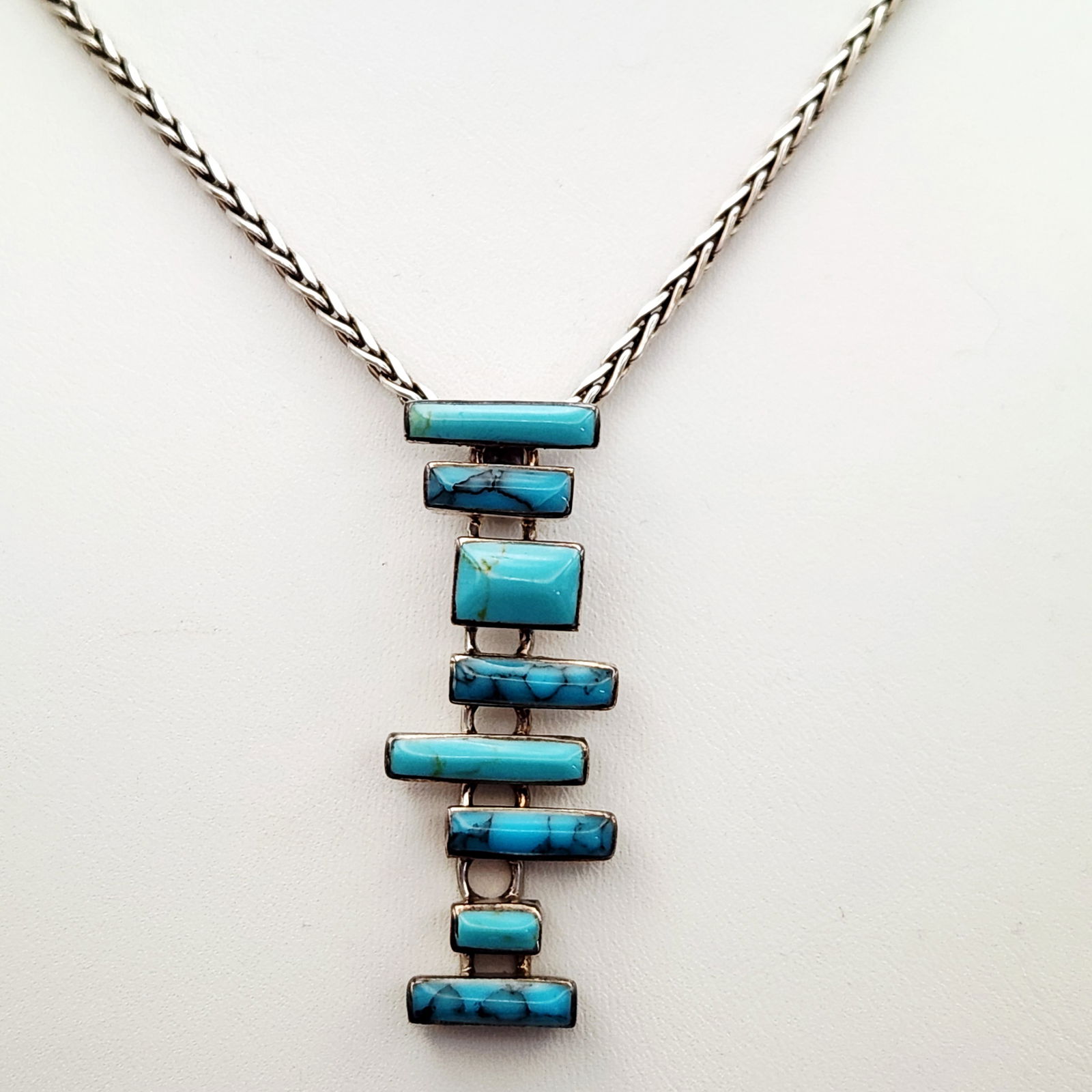 Sterling Turquoise Modernist Necklace 35.2 Grams: This necklace features a sterling silver pendant designed in a modernist style, composed of multiple rectangular and square-cut turquoise stones. The stones are arranged horizontally and secured in in