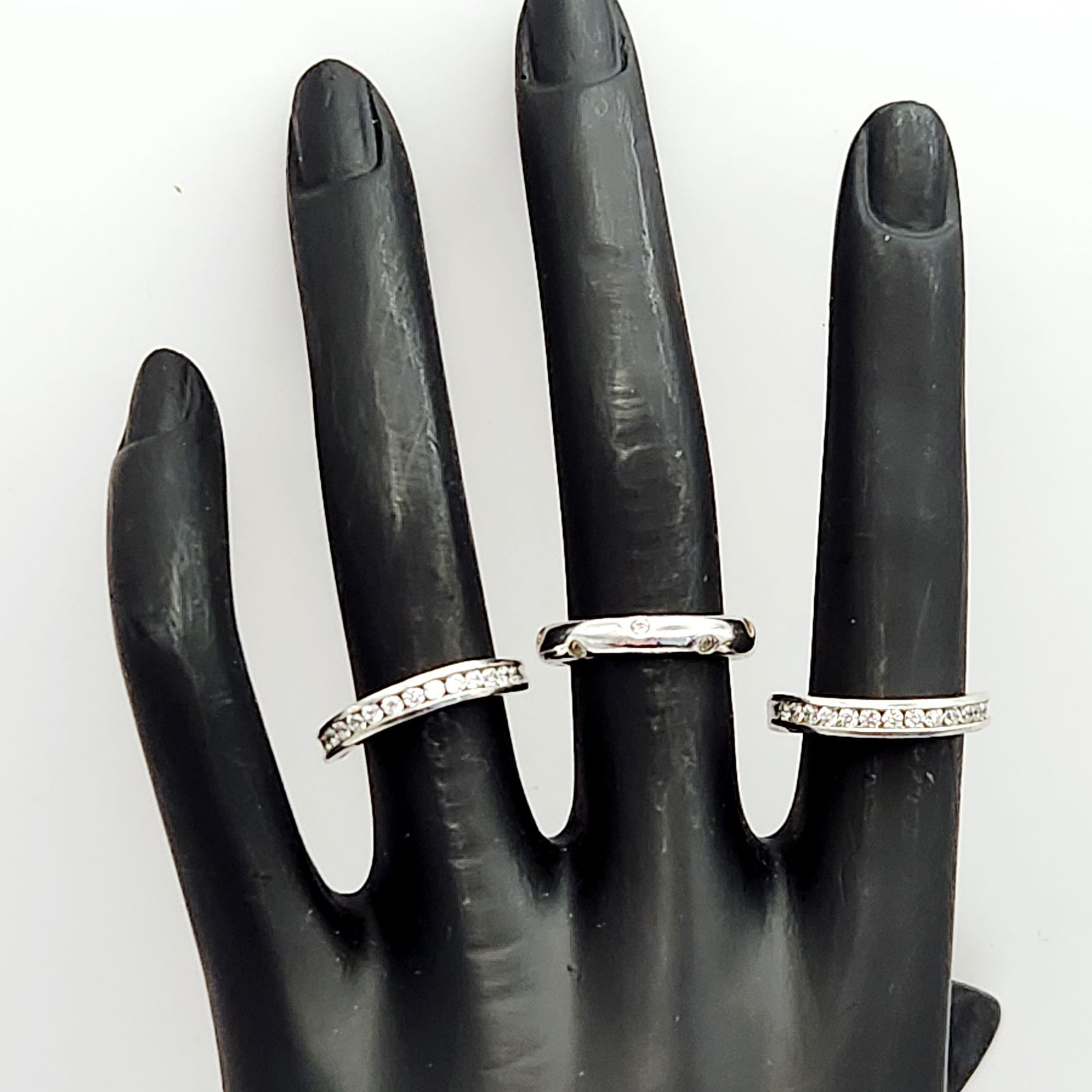 Sterling Silver & Cubic Zirconia Rings 7 Grams: A trio of contemporary sterling silver rings featuring colorless stones. The group includes two matching contoured bands with channel-set stones and a rounded band with flush-set stones. Interior hall