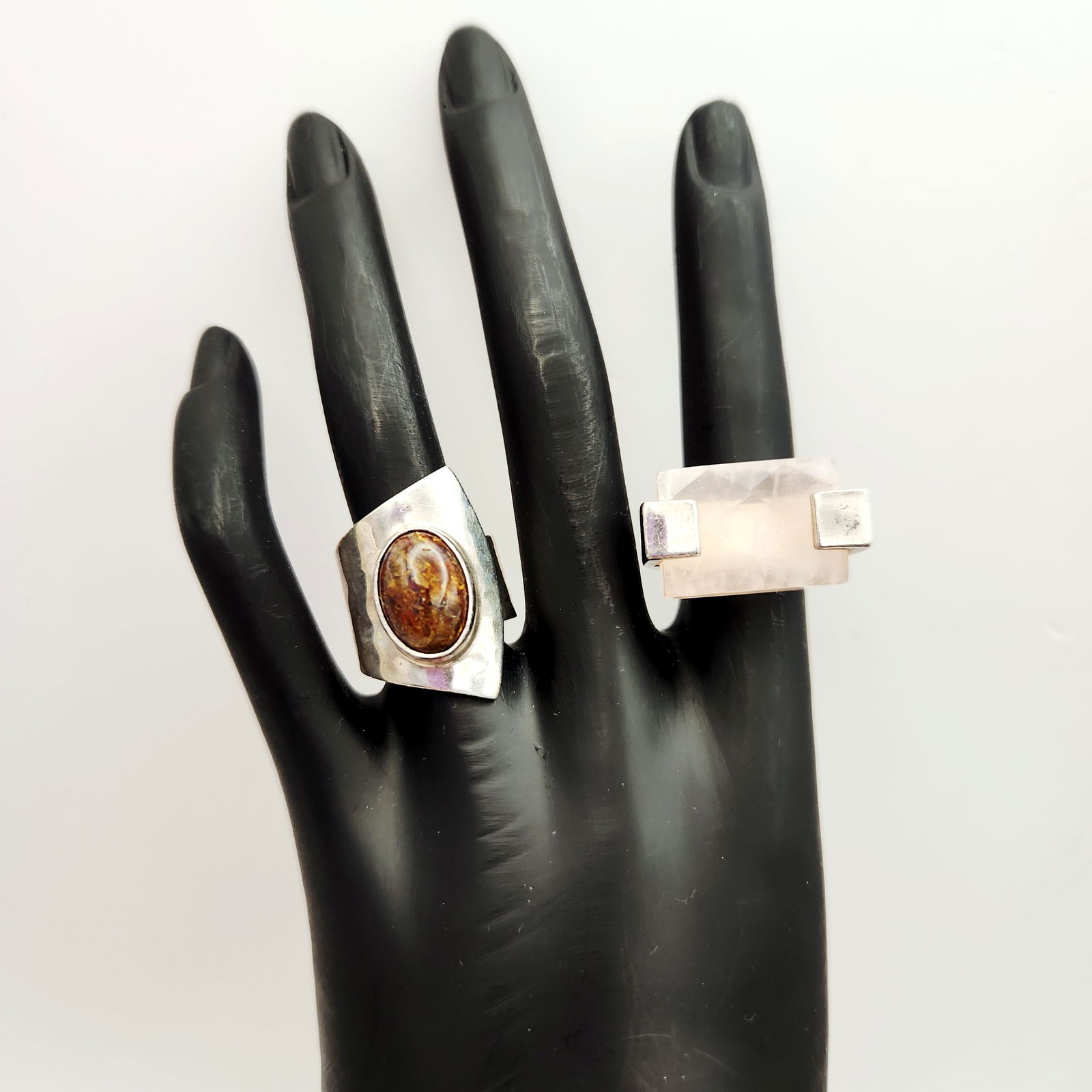 Sterling Semi-Precious Stone Rings 29.4 Grams: A group of two contemporary sterling silver rings featuring large semi-precious stones. One ring is set with a rectangular, faceted, pale pink stone, likely rose quartz, on a wide band hallmarked 925.