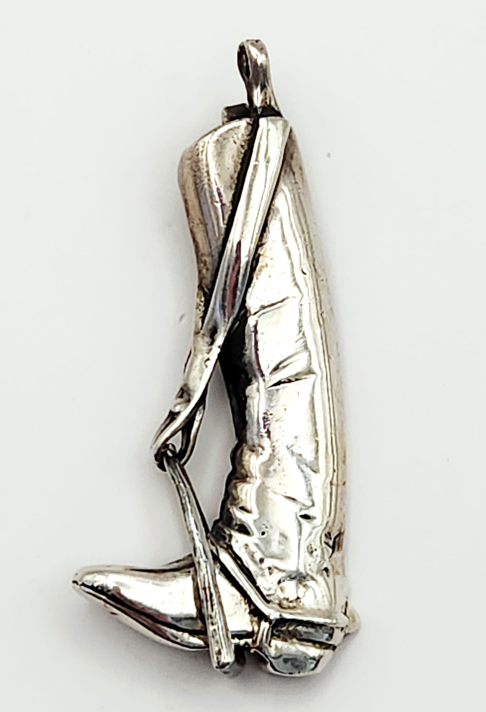 Sterling Equestrian Riding Boot Pendant 21.2 Grams: This equestrian-themed sterling pendant features a representational design of a tall riding boot with an integrated riding crop. The piece is constructed with a hollow back and a textured, darkened