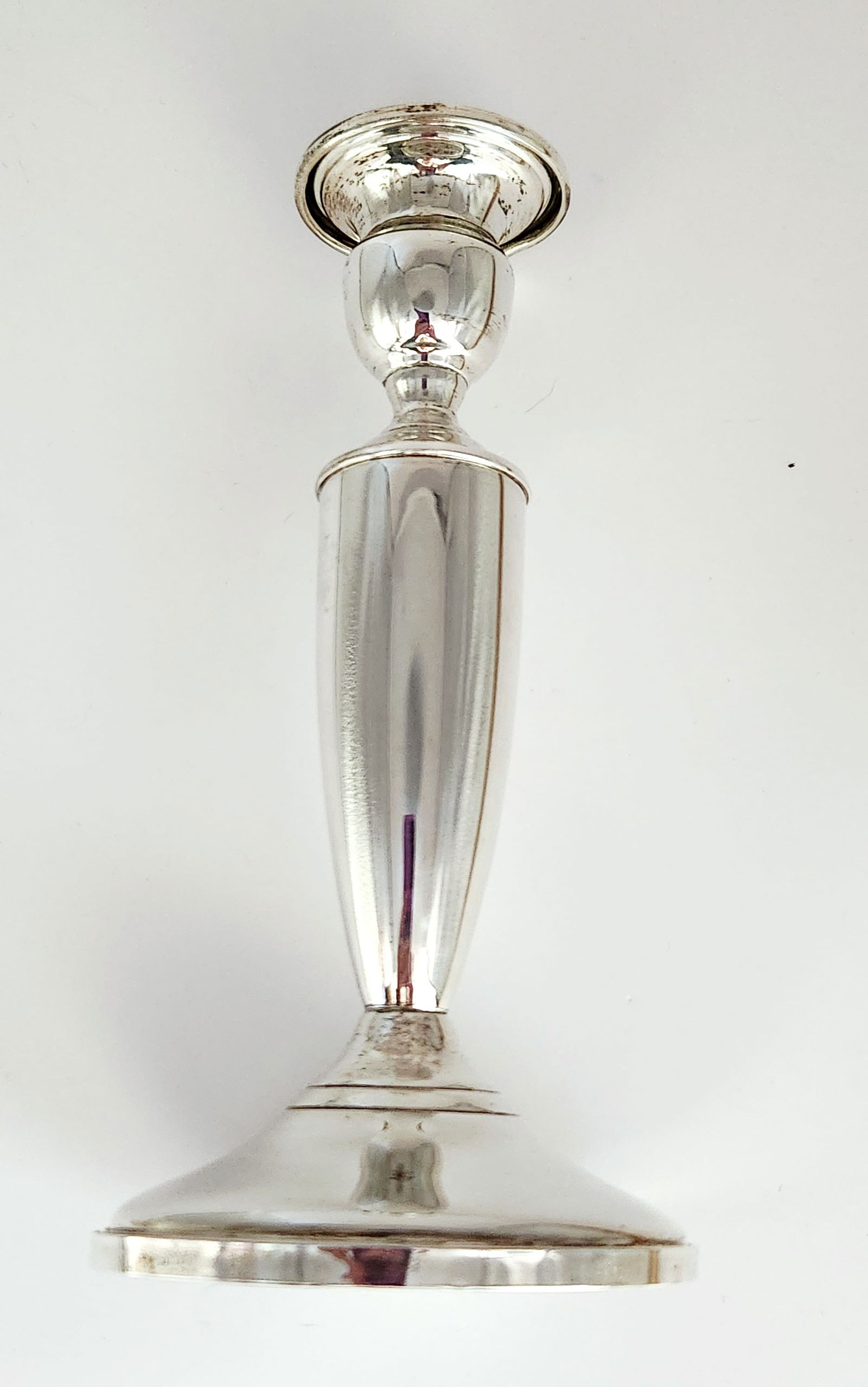 Towle Sterling Weighted Candlestick 13.18 Ounces: A single weighted sterling silver candlestick manufactured by Towle. The piece features a modernist design with a broad circular flared base, a smooth tapered stem, and a simple cup-shaped nozzle.