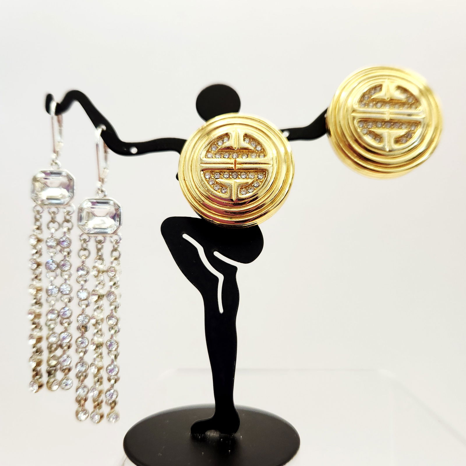 Givenchy Costume Jewelry Earrings: A group of Givenchy costume jewelry earrings. The assortment includes gold-tone circular clip-on earrings featuring a raised geometric logo design accented with inset clear crystals. These earrings