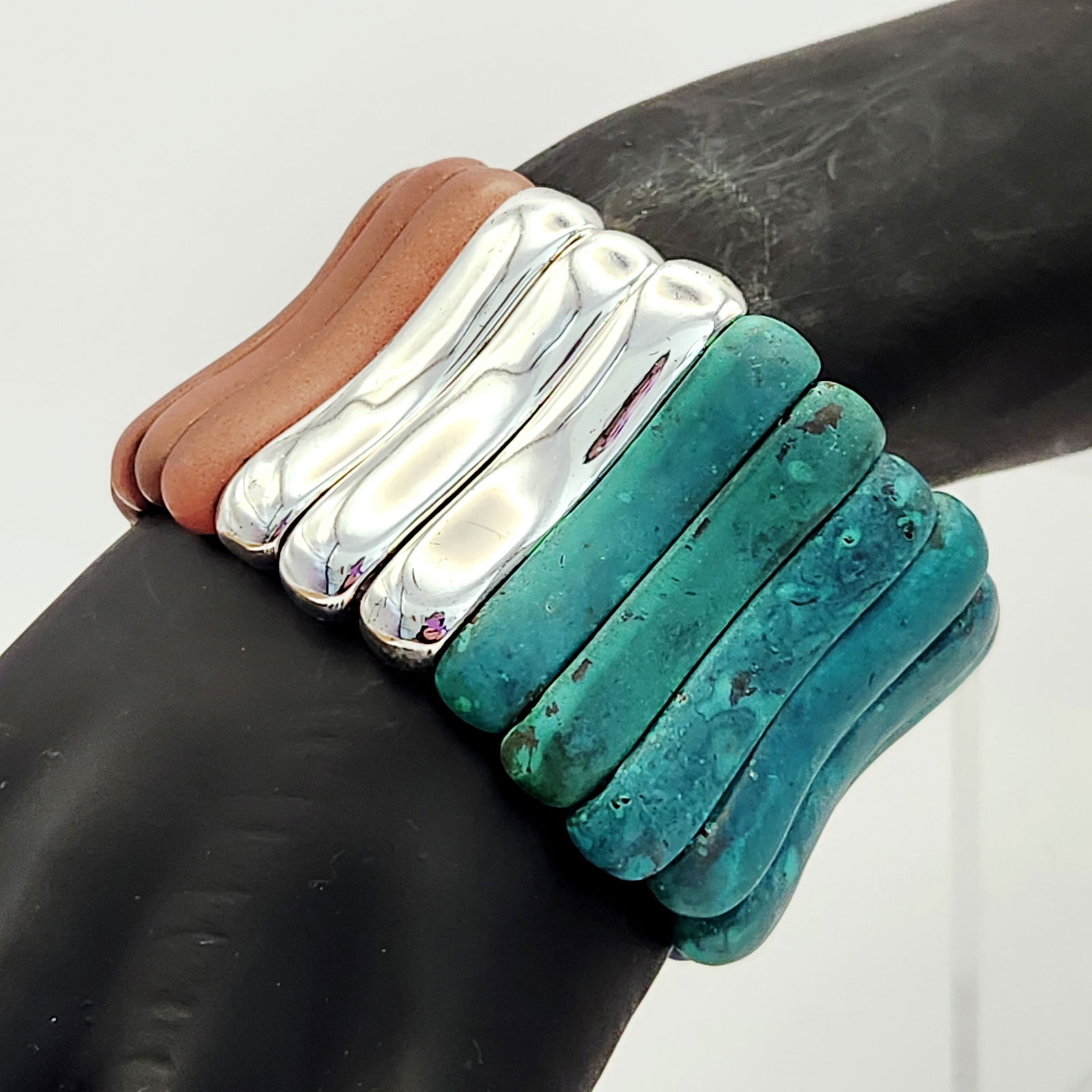 Patina Soho Multi-Color Stone & Silver-Tone Stretch Cuff Bracelet: A wide stretch cuff bracelet of Mexican origin, featuring a series of curved, vertical bar segments. The segments are organized into color blocks consisting of turquoise-hued stone with natural matrix
