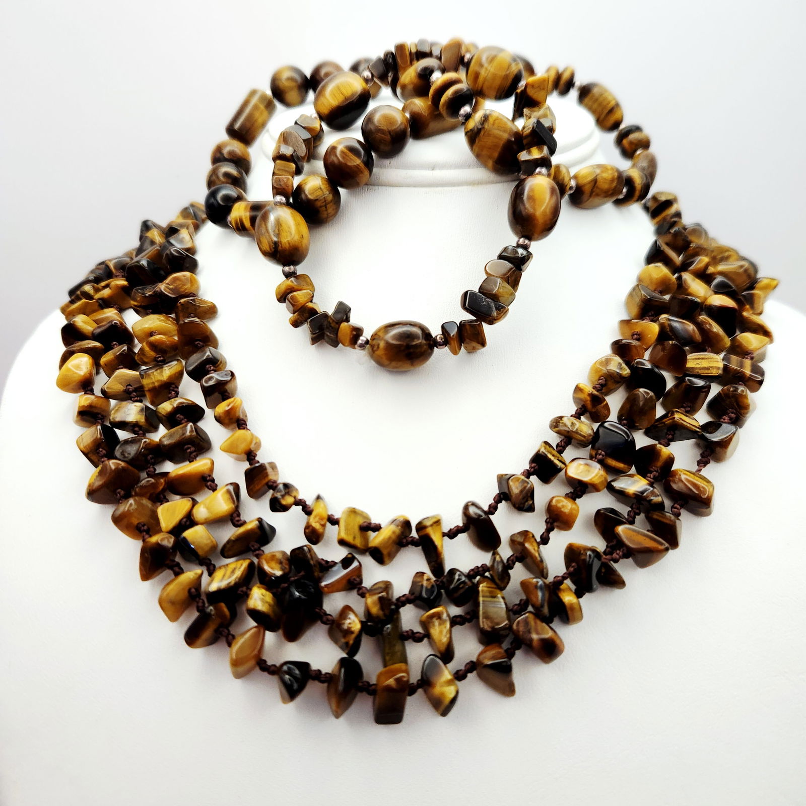 Tiger's Eye Necklace & Bracelets: An assortment of tiger's eye jewelry featuring a single-strand necklace and several stretch bracelets. The necklace is composed of polished tiger's eye chips hand-knotted on a brown cord and finished