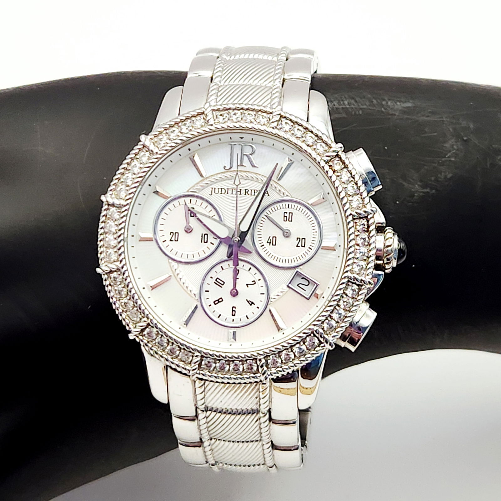 Judith Ripka Stainless Steel Diamonique Chronograph Wristwatch: A Judith Ripka stainless steel chronograph wristwatch featuring a mother of pearl dial with three subdials and a date aperture at the 4 o'clock position. The dial is marked with the JR logo and Judith
