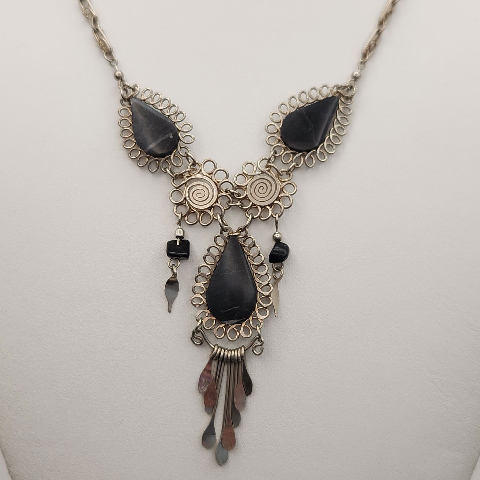 Artisan Silver-Tone & Black Stone Tribal Style Pendant Necklace: This handcrafted necklace features a tribal-influenced design constructed from silver-tone metal and opaque black teardrop-shaped stones. The central pendant assembly is composed of three large teardr