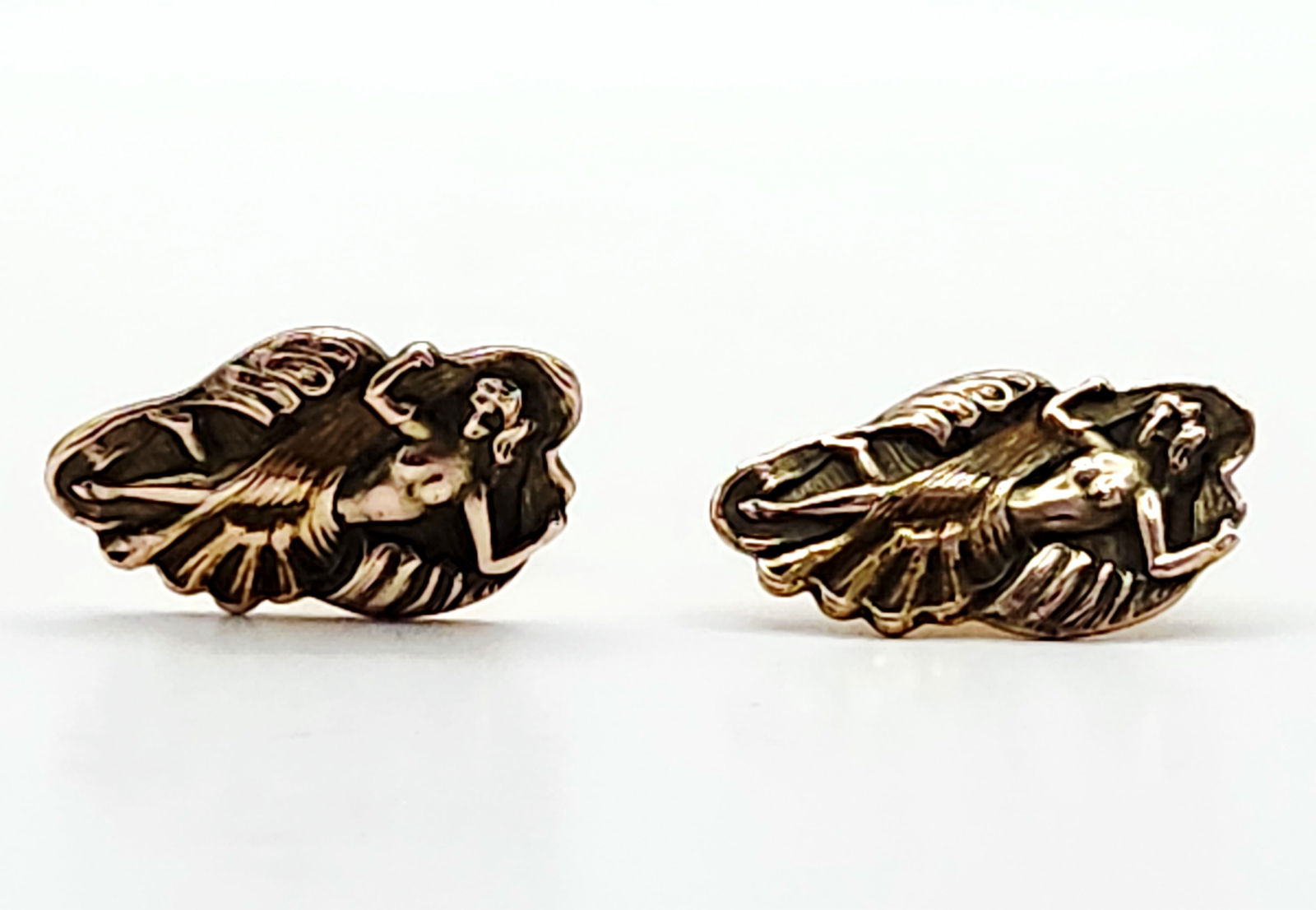 Art Nouveau Style Gilt Metal Cuff Links: This lot features a pair of Art Nouveau style cufflinks, each showcasing a high-relief, three-dimensional reclining nude female figure nestled within organic, foliate scrolls. The cufflinks are crafte