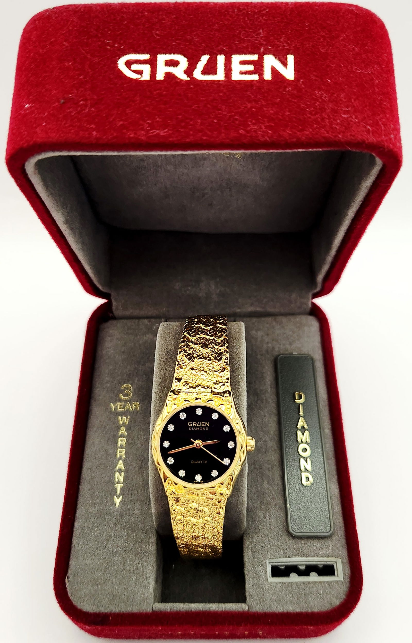 Vintage Gruen Precision Diamond Quartz Ladies Watch: This Gruen Precision Diamond ladies wristwatch features a gold-tone textured nugget style integrated bracelet and matching bezel. The circular black dial is set with twelve small circular diamond hour