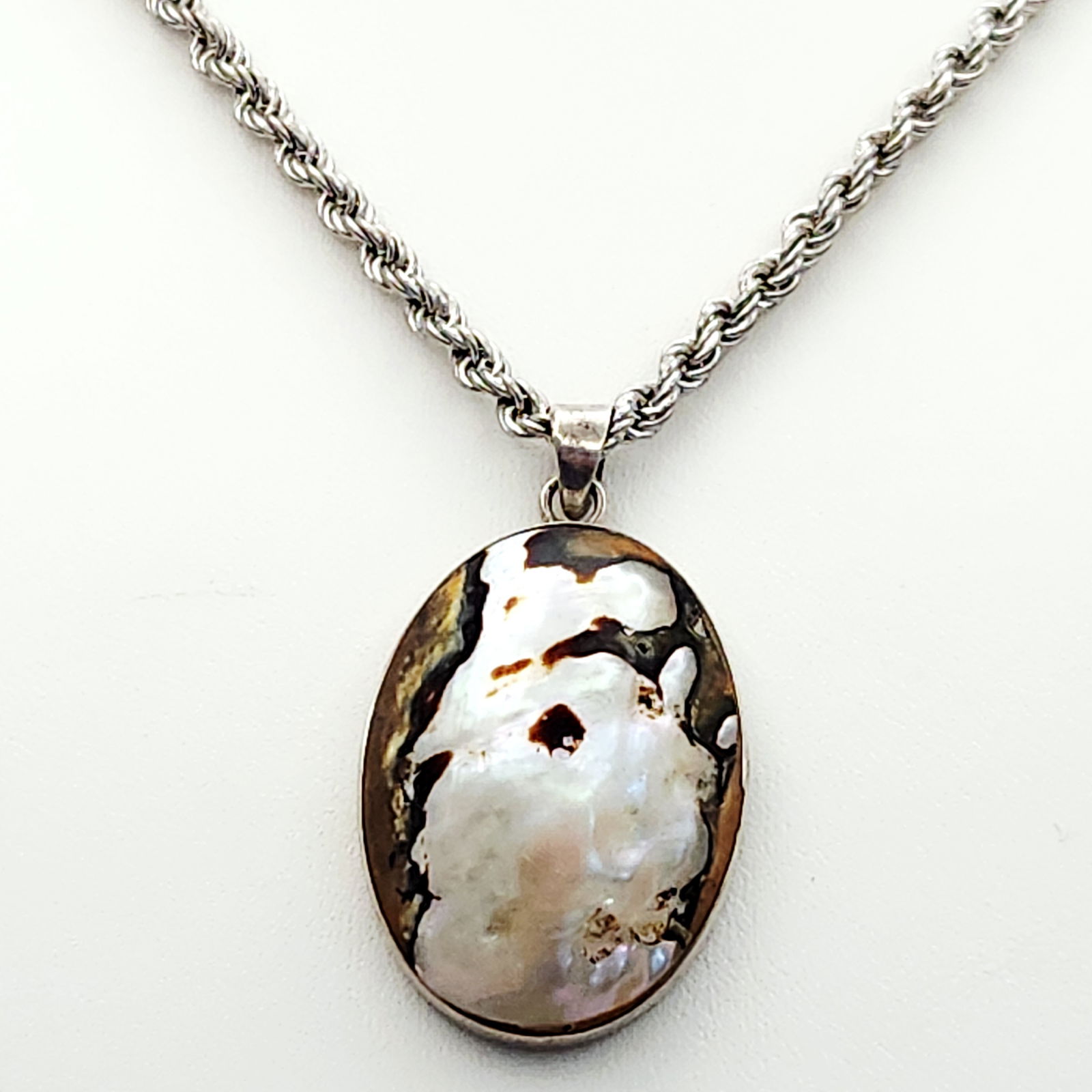 Sterling Blister Pearl Necklace 24 Grams: This necklace features a large oval pendant bezel-set with a natural-form blister pearl or mother-of-pearl cabochon exhibiting iridescent white and dark brown tones. The pendant is suspended from a