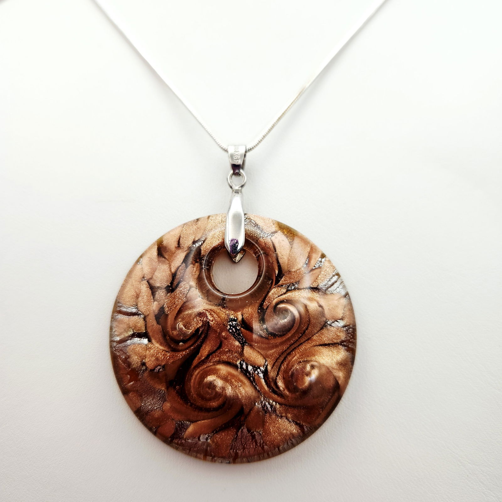 Murano Glass Pendant On Sterling Chain 4.1 Grams: This necklace features a circular art glass pendant suspended on a sterling chain. The pendant is composed of translucent amber-toned glass with internal swirling patterns of gold, silver, and