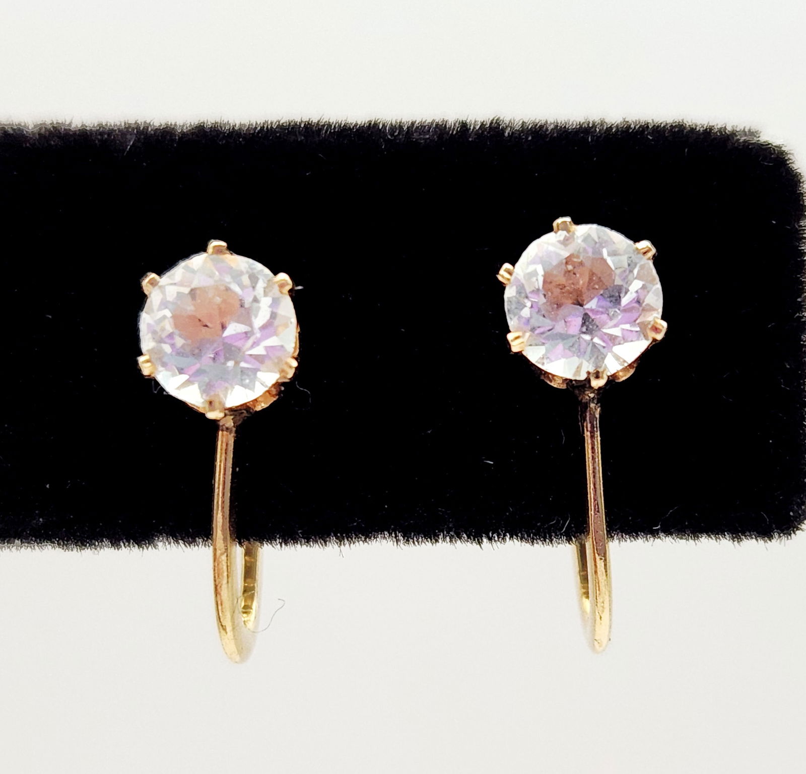 10K Gold & Crystal Earrings 1.2 Gram: A pair of vintage screw-back earrings crafted in 10-karat yellow gold. Each earring features a round-cut colorless gemstone secured in a six-prong basket setting. The earrings are equipped with