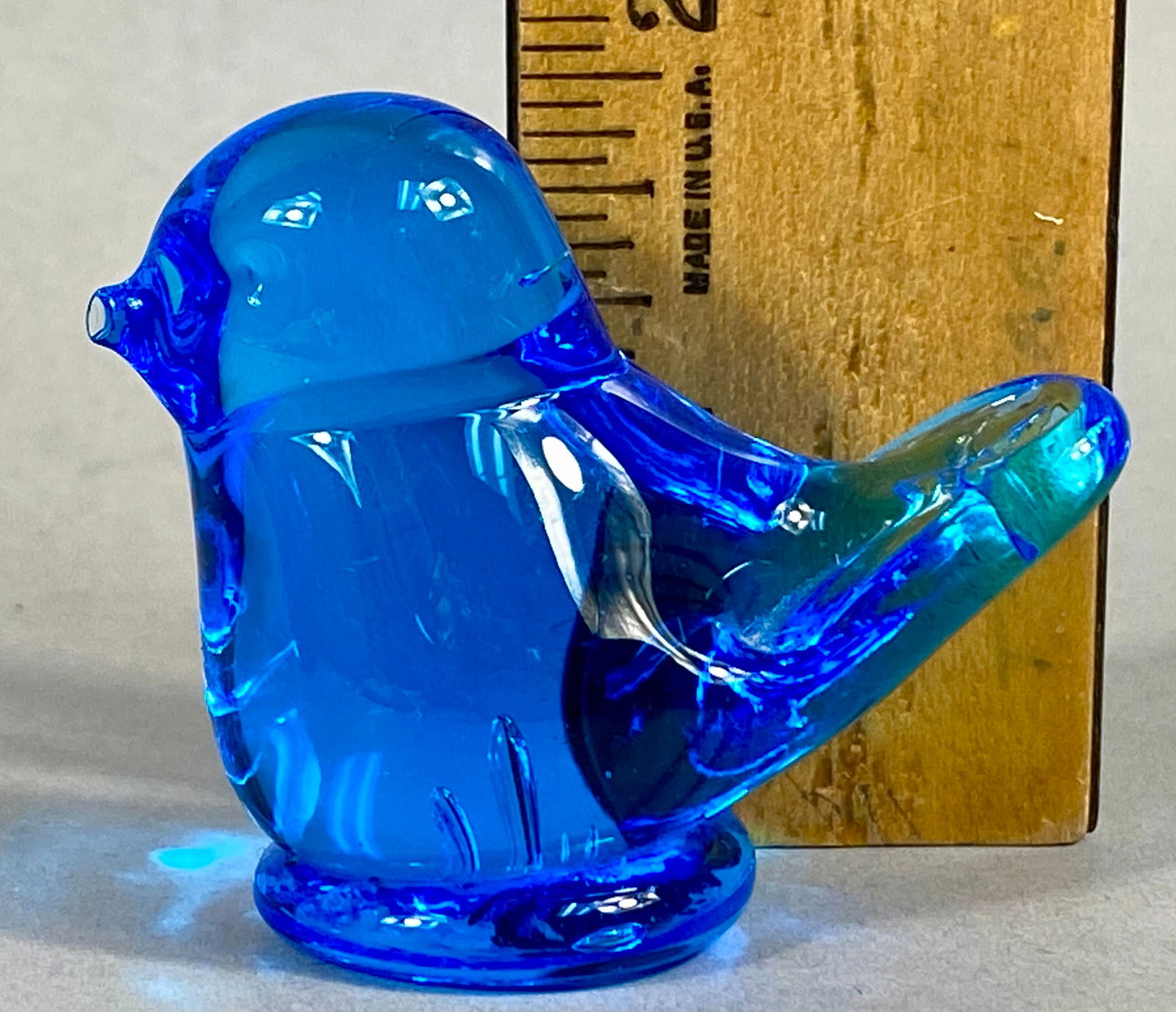 Two Bluebird of Happiness Art Glass Figurines by Leo Ward and Ron Ray: Two Bluebird of Happiness art glass figurines crafted from translucent cobalt blue glass. The lot includes a larger bird perched atop a spherical base and a smaller standalone bird figurine. Both piec