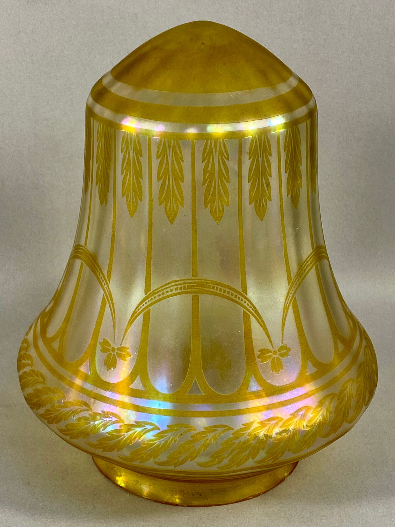 An Early 20th Century Iridescent Art Glass Lamp Shade with Neoclassical Decoration: An iridescent art glass lamp shade featuring an aurene-style finish with golden-yellow neoclassical motifs. The bell-shaped form is decorated with an etched or applied pattern consisting of vertical s