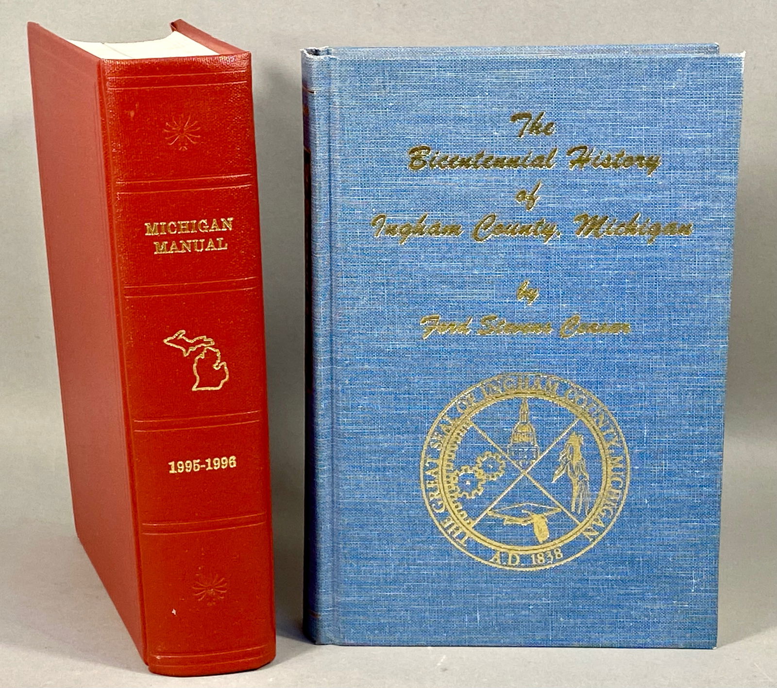 Two Michigan State and Local History Hardcover Books: This lot consists of two hardcover volumes pertaining to Michigan history. The first item is the Michigan Manual 1995-1996, published by the Michigan Legislative Council. The volume is bound in red te