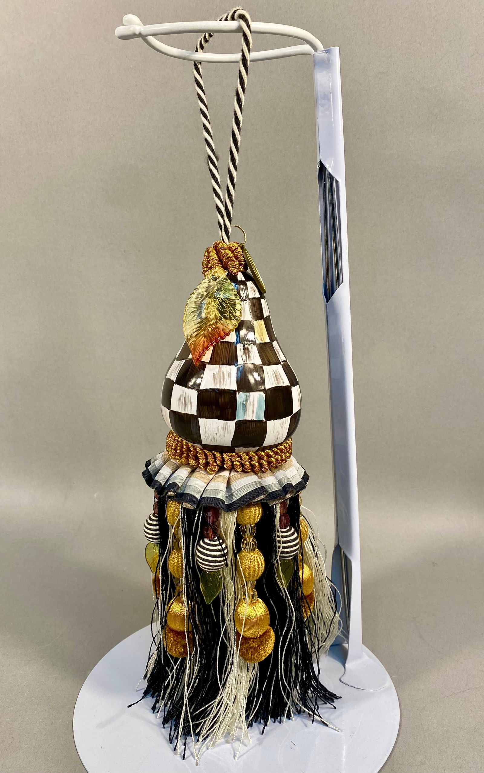 MacKenzie-Childs Courtly Check Pear Tassel: A MacKenzie-Childs Courtly Check pear tassel featuring a ceramic pear-shaped head hand-painted in the signature black and white checkered pattern with iridescent highlights. The piece is suspended fro