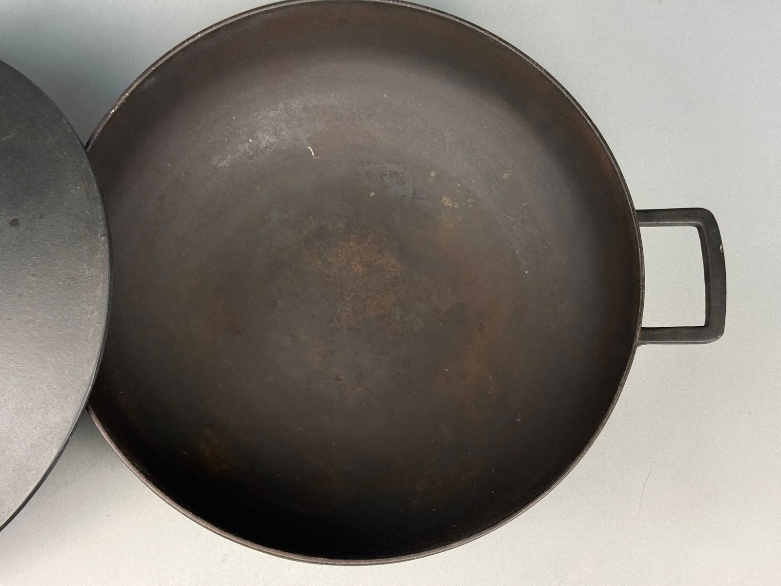 Large Cast Iron Wok w Lid: A modernist casserole dish or saute pan or wok featuring a matte black finish. The circular body is designed with a low profile and includes two integral square side handles. The matching lid is toppe