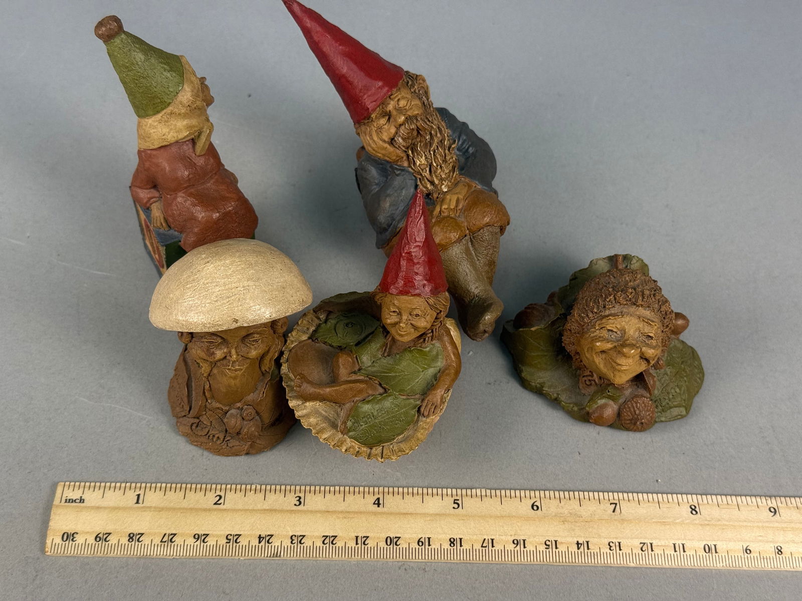 A Collection of Tom Clark Cairn Studio Gnome Figurines: A collection of molded resin figurines designed by artist Tom Clark for Cairn Studio. The sculptures are crafted from a textured composite material painted to simulate wood and organic textures. Hand-