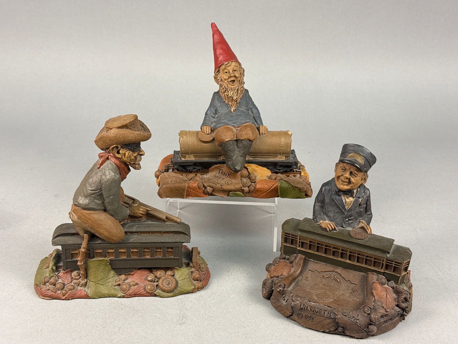 A Trio of Tom Clark Cairn Studio Train Series Resin Figurines: A trio of hand-painted molded resin figurines from the Train Series created by artist Tom Clark for Cairn Studio. The collection includes the figures Jesse, Tank, and Dilworth. Each piece features the
