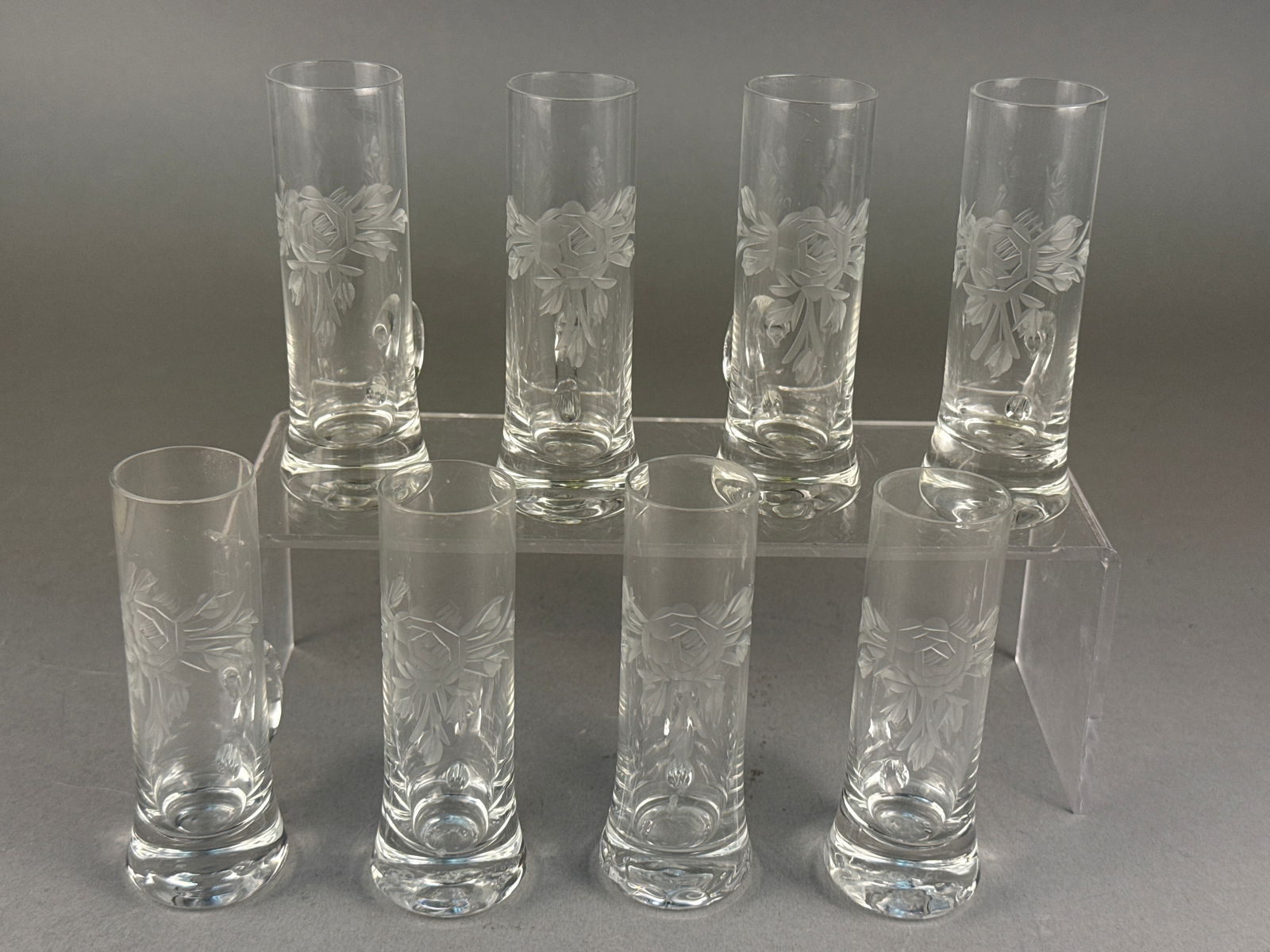 A Set of Pasabahce Etched Glass Cordial Glasses: A set of Pasabahce clear glass cordial or liqueur glasses featuring a wheel-etched rose motif. Each vessel is constructed with a tall, slender cylindrical body and a small loop handle positioned near