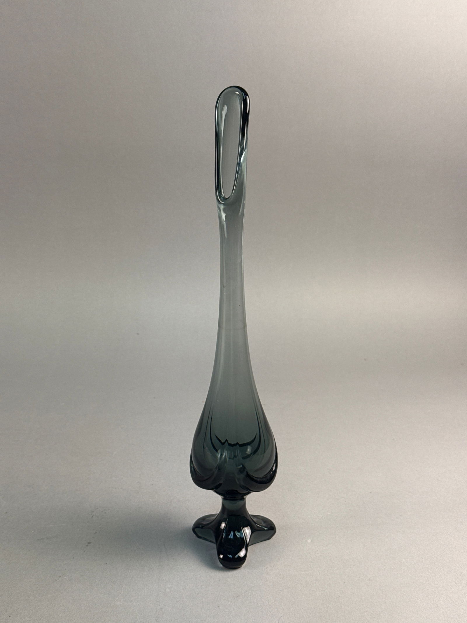 Viking Epic Steel Smoke Drape Tri-Footed Swung Vase: A Viking Epic Steel Smoke charcoal drape tri-footed swung vase. This mid-century modern vessel is crafted from transparent charcoal-colored glass with a high-gloss finish. The form features a bulbous